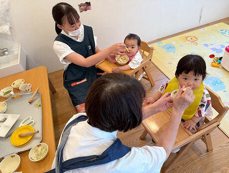 子どもに離乳食を食べさせる職員