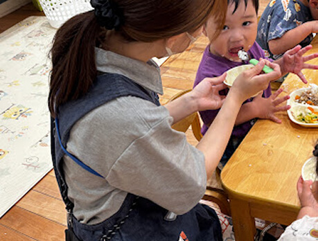 子どもにご飯を食べさせる職員